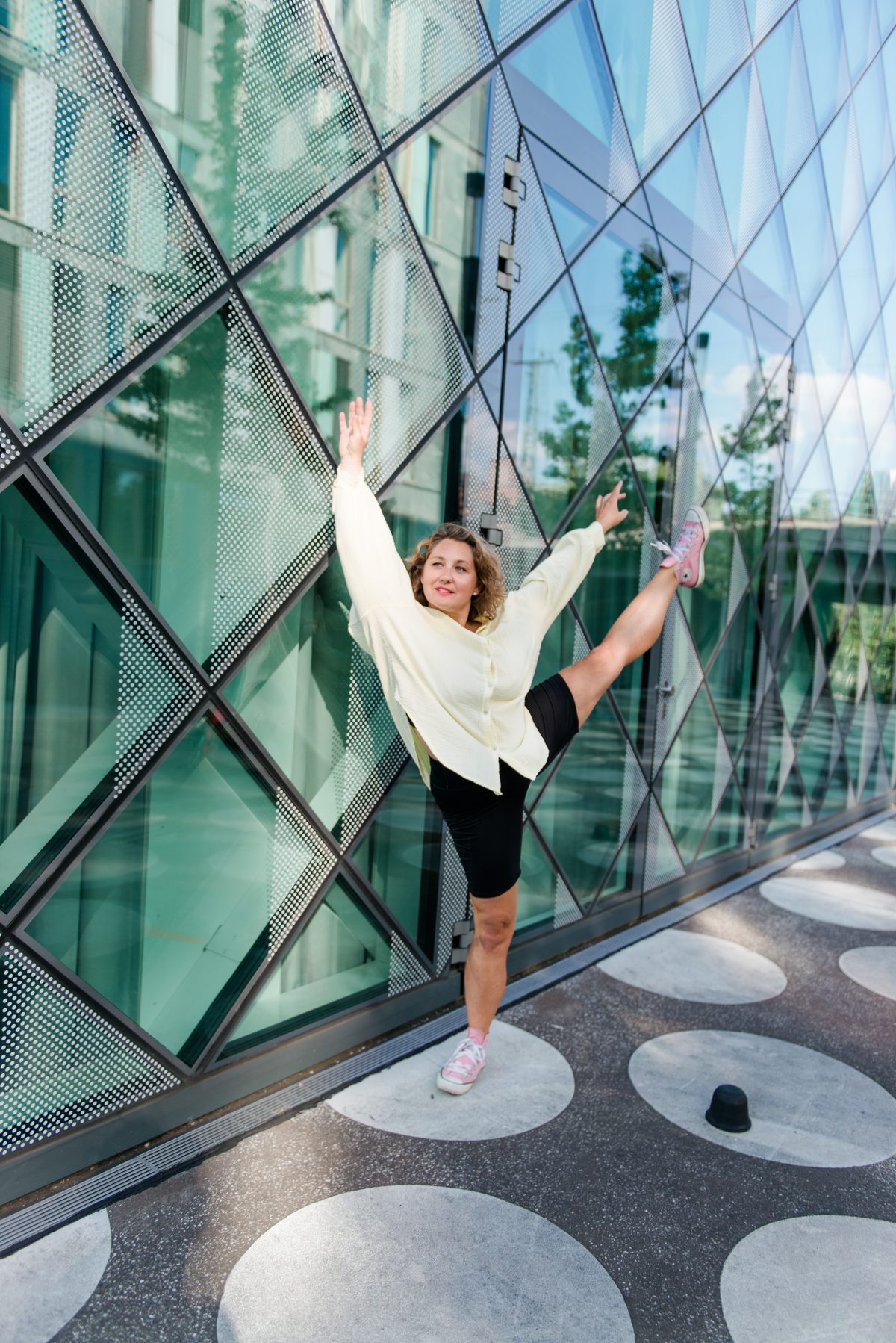 Natalie kicking her leg up in joy in front of a glass facade