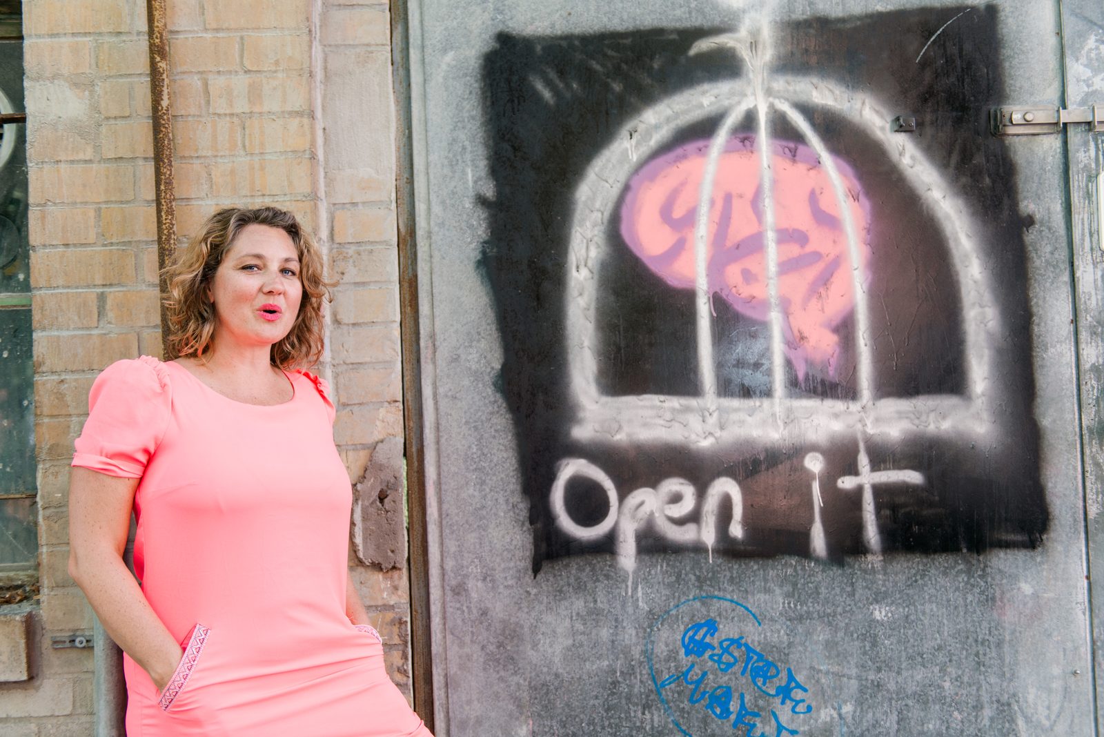 Natalie beside a graffiti of a brain locked behind bars with the words Open it